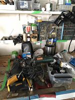 Overview of assorted hardware items including a DeWalt hand saw, Walter electric polisher/grinder, measuring tape, various small containers and hardware items on a bench.