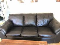 Front view of three-seat brown leather sofa bed