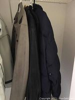Four men's coats hanging in closet showing colors and styles