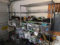 Full view of two metal wire shelving units with various plastic bins and items stored on shelves (contents not included). Taller unit has six shelves and wheels; shorter unit has five shelves.