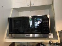 Front view of stainless steel Panasonic microwave on shelf