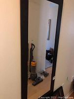 Full view of rectangular wall hung mirror with black frame and beveled edge, reflection shows room