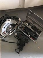Black & Decker circular saw, rotary tool, and carrying case laid on floor.