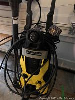 Front view of the yellow and black Karcher pressure washer showing its compact design and hard plastic wheels.
