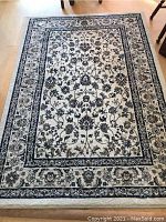 Full view of the rectangular rug on a hardwood floor showing the floral design and borders