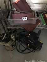 Mastercraft belt sander and Porter Cable router with sanding belts in plastic container on metal shelving