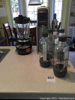 Photo showing SodaStream soda maker, four SodaStream bottles, unopened CO2 carbonator, and Hamilton Beach blender on countertop