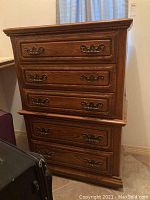 Full view of the tall 5-drawer wooden chest showing the design, drawer handles, and overall condition.