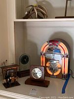 Full lot photo showing two clocks, a metal musical box figurine, and a jukebox cassette player.