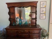 Front view of dresser with mirror showing carved wooden frame, drawers and decorative top molding.