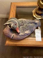 Side view of the decorative duck statue showing detailed feather texture and realistic painting on a wooden table.