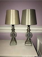 Pair of 16-inch table lamps with gold fabric shades, plaster bases with ornate designs, and crackled glass globes on a white surface.