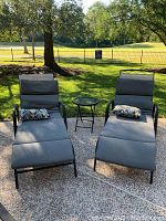Two chaise lounge chairs with cushions and round side table on patio