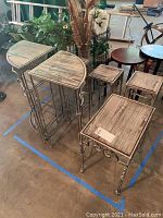 View of three corner tables and three plant stands showing metal frames with intricate scrollwork and distressed wood tops