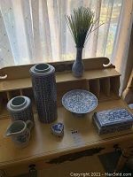 Photo showing three blue and white ceramic vases, the serving dish, cream jar, and two jewelry boxes grouped on a desk.