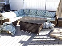 Full view of four-piece wicker sectional with cushions, ottoman and side table (fire table excluded)