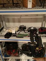 Canon AE-1 Program and Minolta 35mm cameras on shelf with flash and vintage phone.