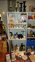 Overview of shelving unit displaying candle holders, figurines, soap dispensers, and other decorative items in assorted finishes and materials.