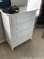 Front view of the white wooden chest of drawers showing all four drawers and white knobs.