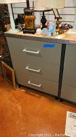 Full view of the Coleman metal cabinet with three drawers and contents on top for scale.