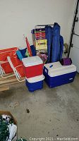 Group photo showing all items in the lot including coolers, chairs, umbrellas, and croquet set in box