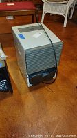 Dehumidifier with visible side and front views, showing power cord and damaged water tank area.