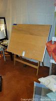 Front view of wooden adjustable drafting table showing wood surface and angled stand.