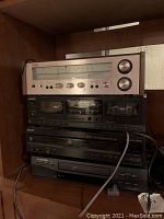 Photo showing stacked audio components: Technics SA-80 receiver on top, Sony stereo cassette deck, Sony CD player, and Mitsubishi VHS player below, all situated on a shelf.