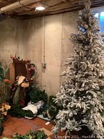 Photo showing the artificial flocked Christmas tree, some green garlands, and part of the Santa figurine.