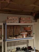 Shelf showing decorative luggage in pink floral and solid pink colors with lamp and candle holders below.