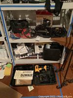 Shelf view showing various power tools including Skil sander, Dremel rotary tool, Wagner Power Painter Plus with box and manual, and Dewalt drill kit in carrying case at floor level.