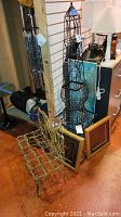 Lot display showing metal wind chimes, metal topiary sculpture, framed wall art pieces, and metal bench with owl decoration.