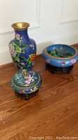 Photo showing blue decorative cloisonné vase with floral and butterfly motifs alongside matching covered bowl and planter.