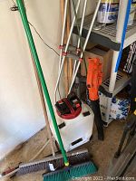 Photo showing Black & Decker blower, broom handles, crutches, post hole digger in storage area.