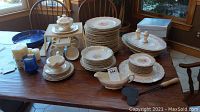 Wide shot of full Keystone Canonsburg Pottery china set arranged on wood table showing plates, cups, bowls, platters, candles, and gravy boat.