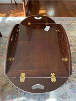 Top view of wooden coffee table showing drop sides and brass hinges, with integrated handles cut into wood.