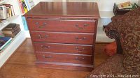 Front view of wooden 4-drawer file cabinet showing drawer handles and finish.