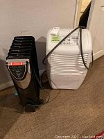 Malco oil filled heater and Whirlpool dehumidifier side by side on carpeted floor.