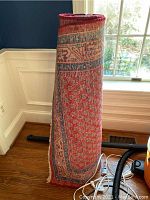 Image showing the rolled wool pile rug standing upright near a window with sunlight.