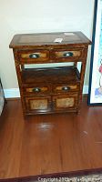 Front view of wooden side table showing two small drawers at top, open shelf, two drawers below, and cabinet doors at bottom with metal handles.