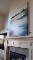 Front view of the signed abstract landscape canvas painting hanging on wall above fireplace.