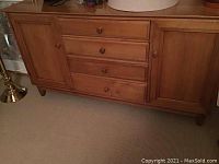 Full view of wood cabinet showing front with four drawers in the middle and two side doors