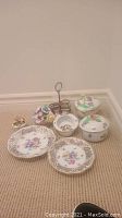 Full set of 8 decorative china pieces arranged on carpeted floor, showing floral designs and diversity of items.