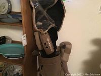 Photo showing a beige golf bag containing various left-handed golf clubs including woods and irons, some with head covers