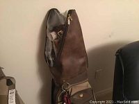 Golf bag standing upright next to a chair, showing part of the full set including clubs and accessories.