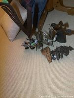 All metal art items arranged on carpeted floor showing various metal roosters, candle holder, and drifting wood art