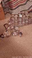 Wide shot of the entire silver plated tea set, wine glasses arranged on the large serving tray, and additional pieces displayed on the carpet.