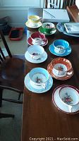 Eight bone china teacups and saucers arranged on table, assorted colors