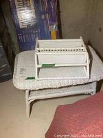 White wicker wall shelf resting on top of white wicker table in basement.