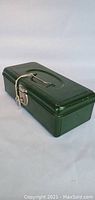 Side view of green metal fishing tackle box showing handle and latch secured with string and key.